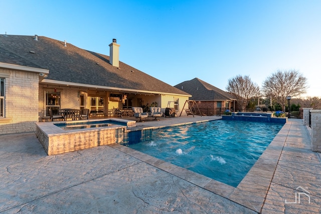 view of pool with fence, a patio area, and a pool with connected hot tub
