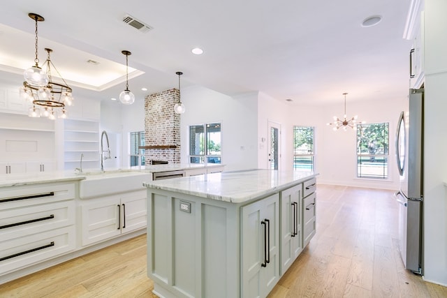 kitchen featuring white cabinets, light wood-style flooring, a sink, freestanding refrigerator, and an inviting chandelier