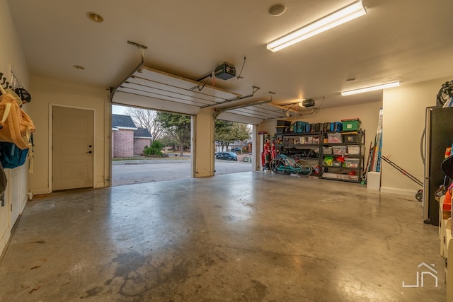 garage with a garage door opener and freestanding refrigerator