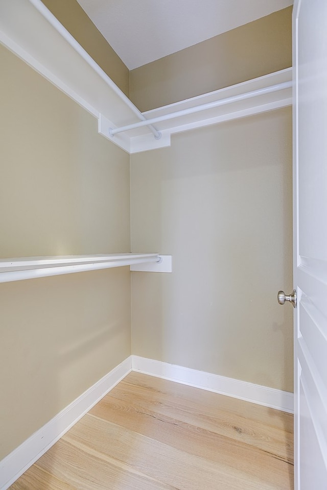walk in closet with light wood-style floors