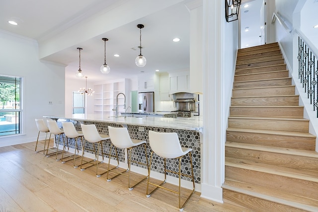 kitchen featuring stainless steel refrigerator with ice dispenser, a breakfast bar, a sink, and ornamental molding