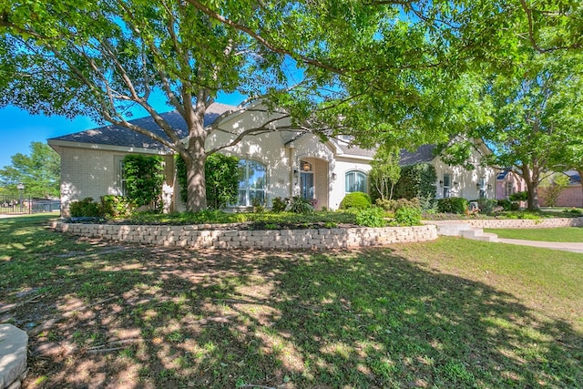 obstructed view of property featuring brick siding, a front lawn, and fence