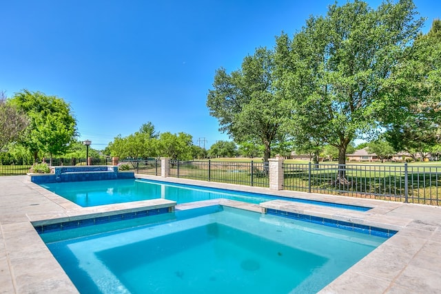 view of swimming pool featuring a pool with connected hot tub and fence