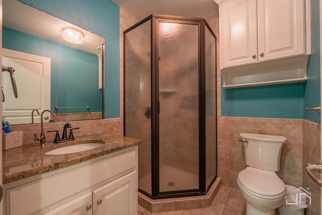 bathroom featuring tile patterned floors, a shower with door, tile walls, and vanity