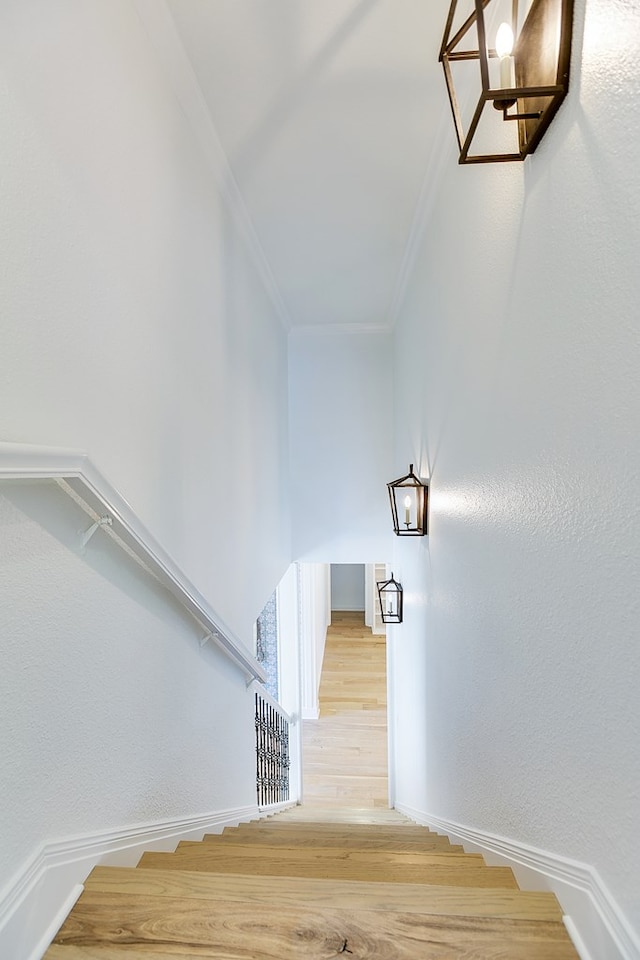 stairs featuring baseboards, crown molding, and wood finished floors