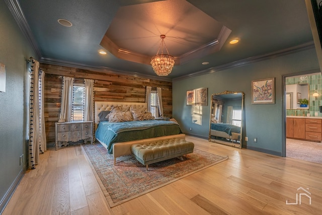 bedroom featuring crown molding, a notable chandelier, a tray ceiling, and light hardwood / wood-style floors