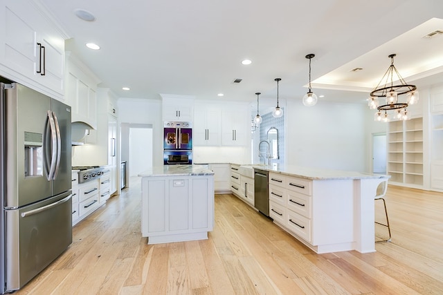 kitchen featuring stainless steel appliances, a large island, visible vents, ornamental molding, and light wood-type flooring