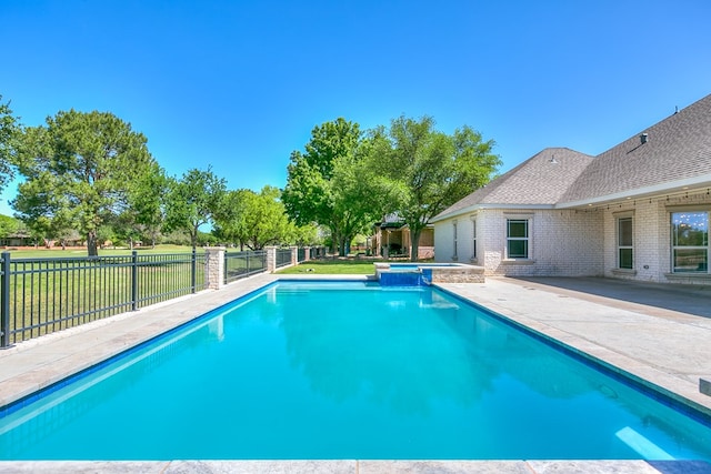 view of swimming pool featuring a yard, a patio area, a pool with connected hot tub, and fence