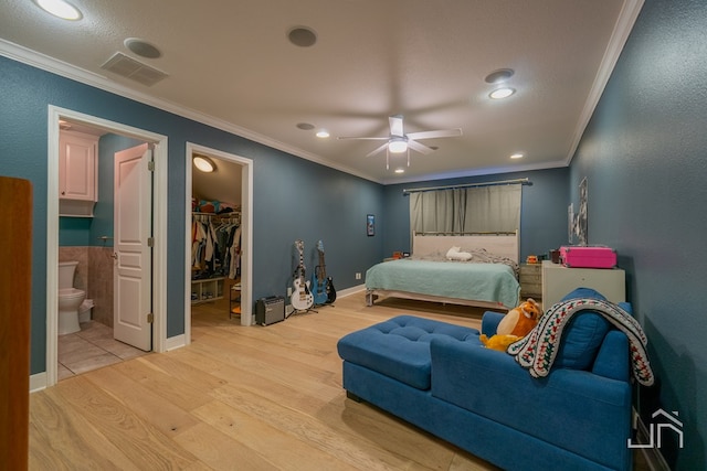 bedroom with ornamental molding, a spacious closet, ceiling fan, light hardwood / wood-style floors, and ensuite bath