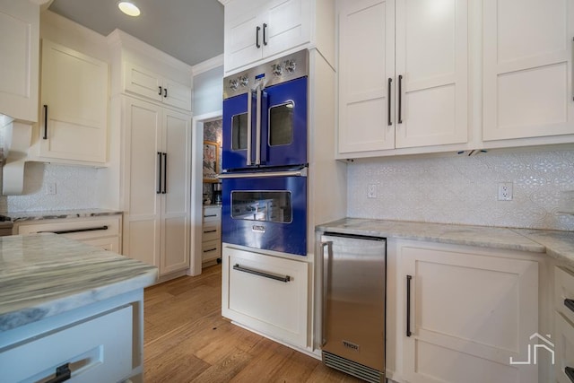 kitchen featuring white cabinetry, double wall oven, light stone counters, and light hardwood / wood-style flooring