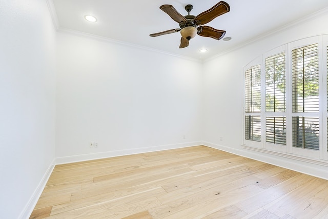 empty room featuring light wood-type flooring, a ceiling fan, baseboards, and crown molding