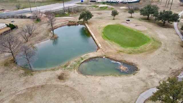 drone / aerial view featuring golf course view and a water view