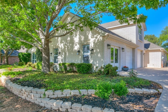 view of front of property with a garage, brick siding, a shingled roof, and concrete driveway