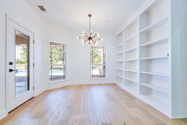 unfurnished dining area featuring light wood finished floors, visible vents, built in features, a notable chandelier, and crown molding
