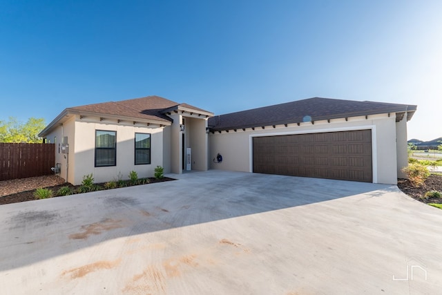 view of front facade featuring stucco siding, driveway, a garage, fence, and a shingled roof