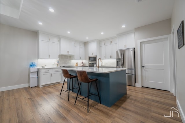 kitchen featuring white cabinets, light countertops, wood finished floors, and appliances with stainless steel finishes
