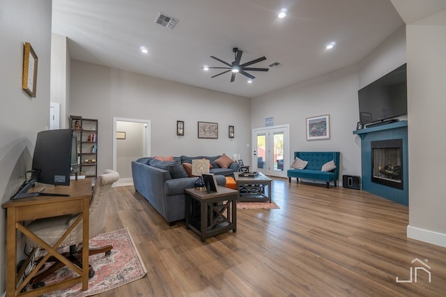 living room with wood finished floors, ceiling fan, a towering ceiling, and visible vents