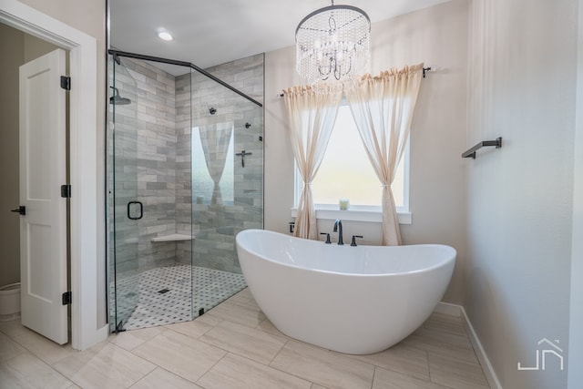 bathroom featuring a shower stall, a freestanding bath, an inviting chandelier, and baseboards
