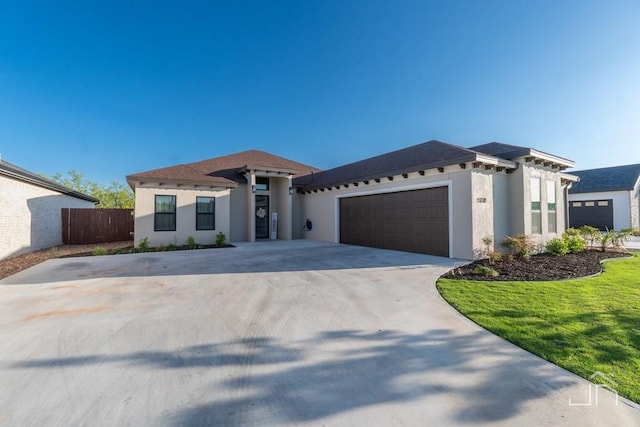 view of front of home with stucco siding, a front yard, fence, an attached garage, and concrete driveway