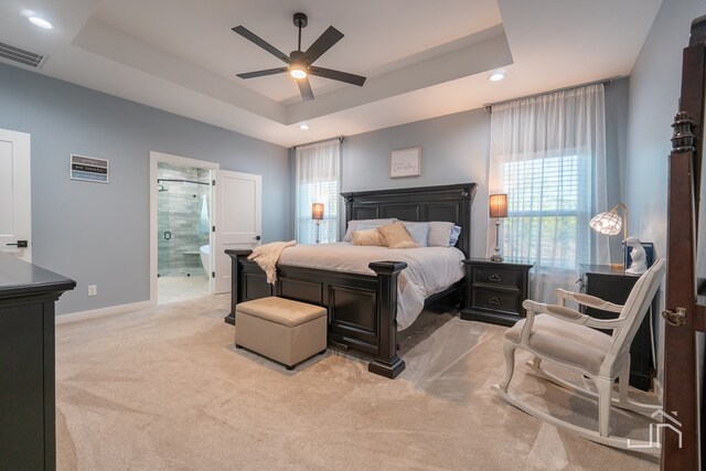 carpeted bedroom featuring ensuite bathroom, baseboards, visible vents, a tray ceiling, and recessed lighting