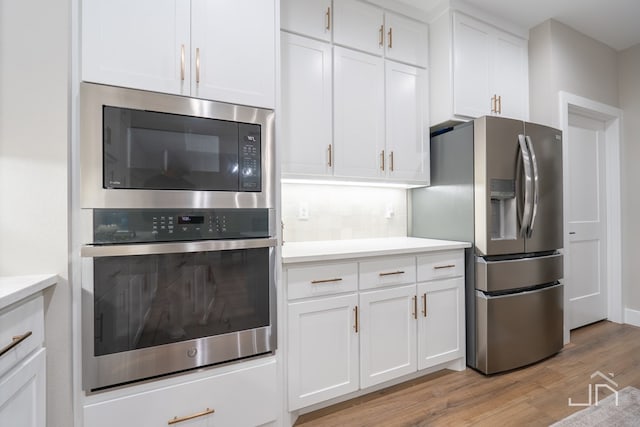 kitchen with light wood-type flooring, appliances with stainless steel finishes, and white cabinetry