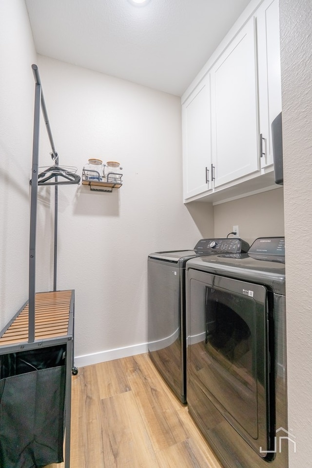 laundry area featuring cabinet space, washing machine and clothes dryer, light wood-style floors, and baseboards