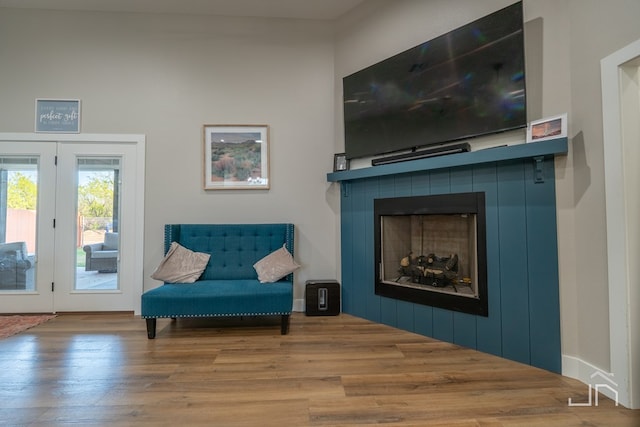 living area with a tiled fireplace, french doors, and wood finished floors