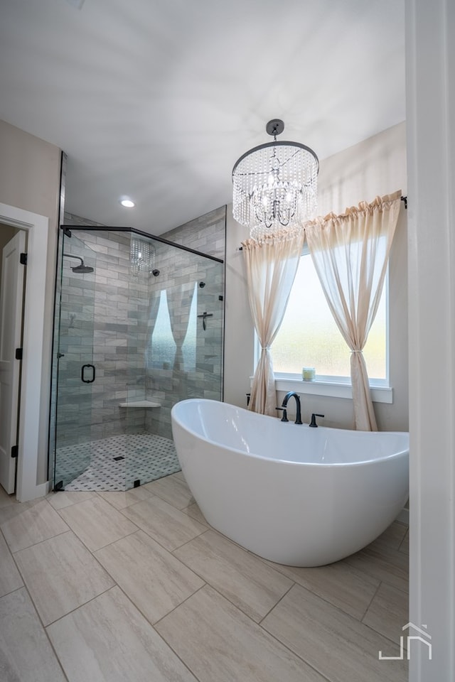 full bath with a shower stall, a notable chandelier, and a freestanding bath