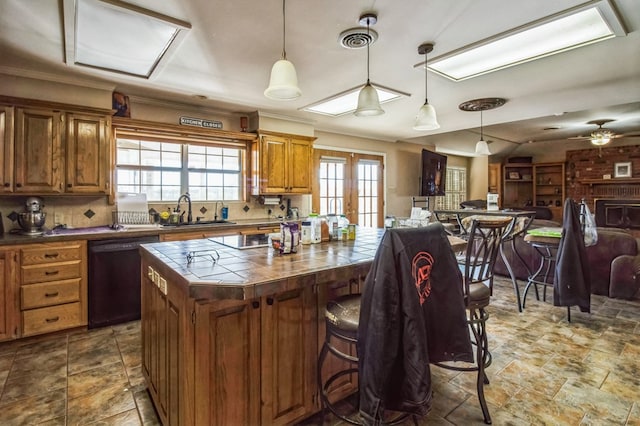 kitchen featuring pendant lighting, sink, a kitchen breakfast bar, a center island, and black dishwasher