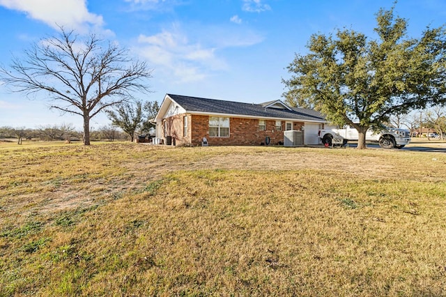 view of side of home featuring a yard and central AC