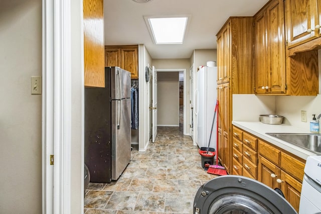 kitchen featuring stainless steel refrigerator, washer / clothes dryer, and sink