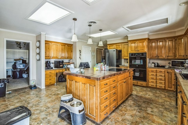 kitchen featuring crown molding, built in desk, hanging light fixtures, a kitchen island, and black appliances