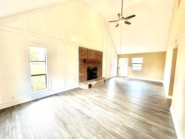 unfurnished living room with a brick fireplace, high vaulted ceiling, hardwood / wood-style floors, and ceiling fan