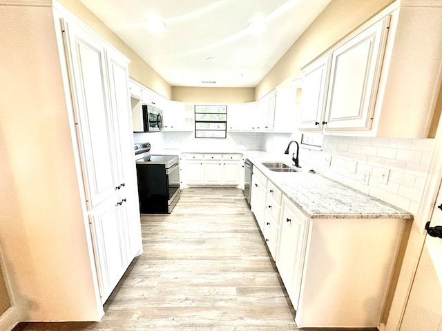 kitchen featuring sink, white cabinetry, light stone counters, light hardwood / wood-style flooring, and appliances with stainless steel finishes