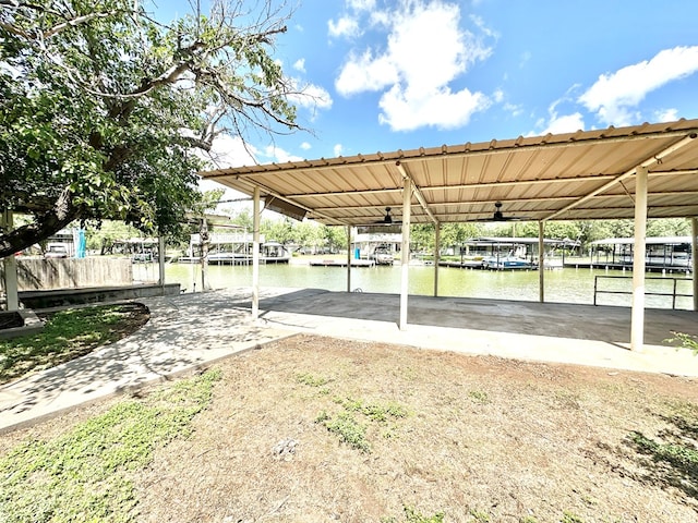 view of vehicle parking with a water view, ceiling fan, and a boat dock