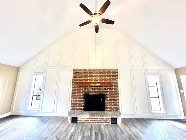 unfurnished living room featuring vaulted ceiling, a brick fireplace, hardwood / wood-style floors, and ceiling fan