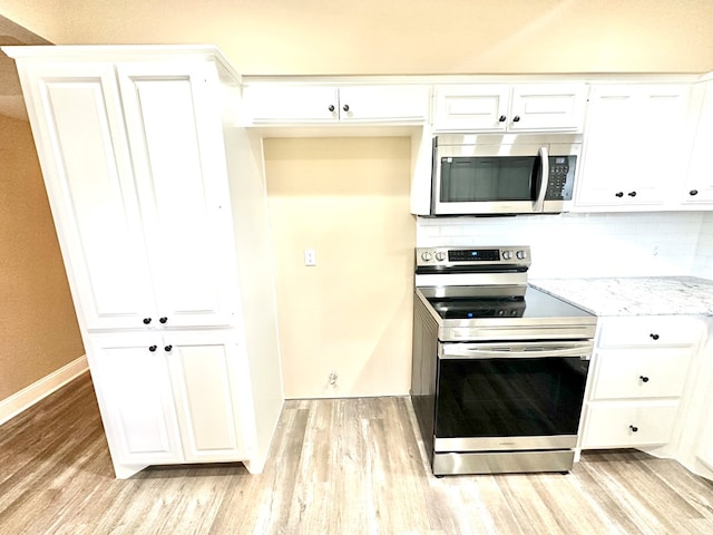 kitchen featuring appliances with stainless steel finishes, tasteful backsplash, white cabinetry, light hardwood / wood-style floors, and light stone countertops