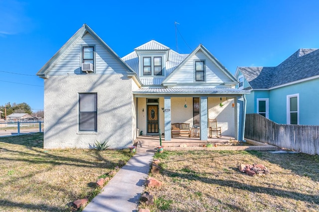 bungalow-style house with metal roof, cooling unit, covered porch, fence, and a front yard