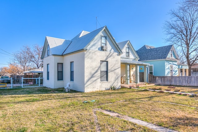 back of property with brick siding, a lawn, metal roof, fence, and cooling unit