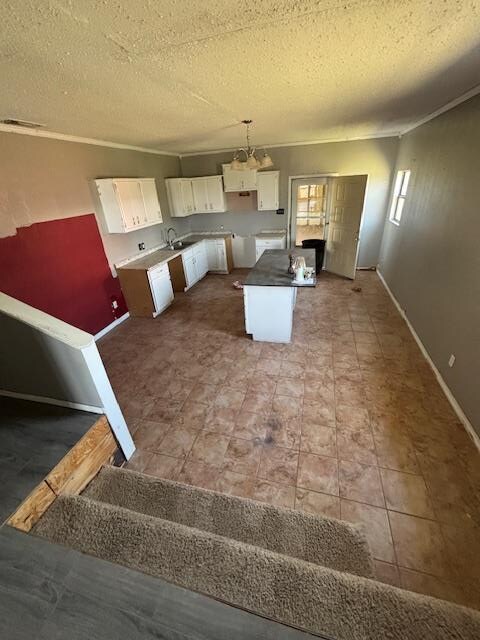 7646 Violet St, San Angelo, TX 76901 - kitchen featuring white cabinetry, a textured ceiling, baseboards, ornamental molding, and decorative light fixtures