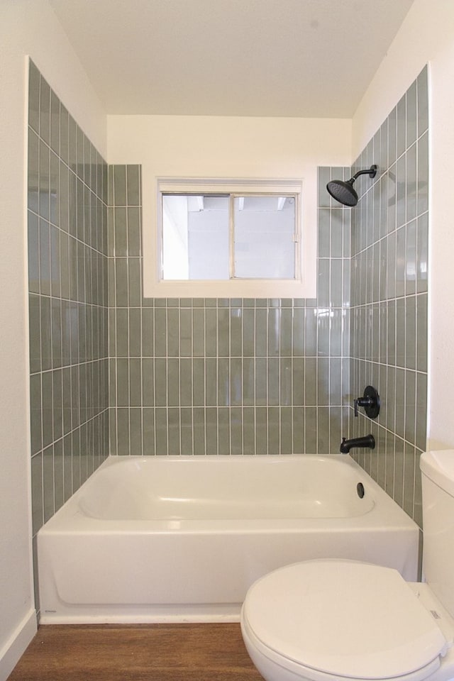 bathroom featuring hardwood / wood-style flooring, tiled shower / bath, and toilet