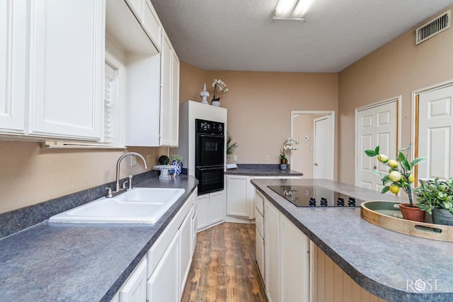 901 Koberlin St, San Angelo, TX 76903 - kitchen with a sink, dark wood-style floors, black appliances, white cabinetry, and a textured ceiling