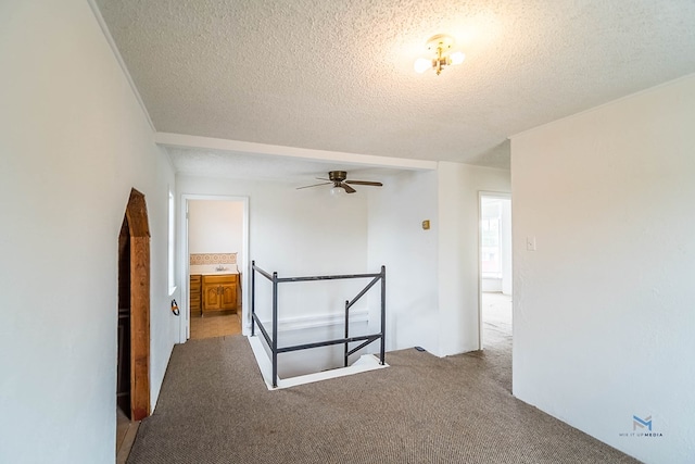 hallway with light carpet and a textured ceiling