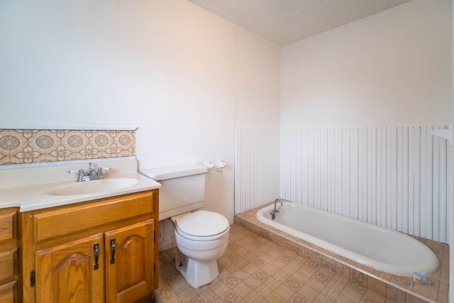 bathroom with vanity, toilet, a textured ceiling, and a washtub