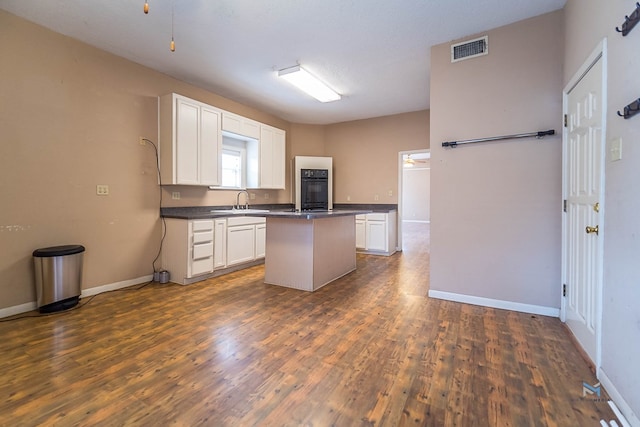 kitchen with dark hardwood / wood-style floors, a center island, sink, and white cabinets