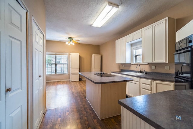 kitchen featuring sink, a kitchen island, black appliances, a textured ceiling, and white cabinets