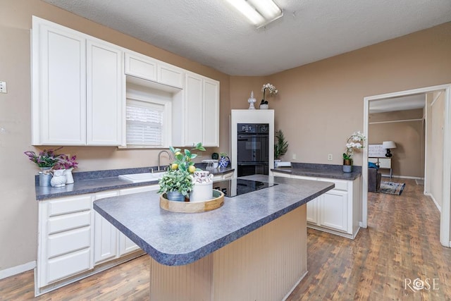 901 Koberlin St, San Angelo, TX 76903 - kitchen featuring a sink, dark countertops, black appliances, wood finished floors, and white cabinetry