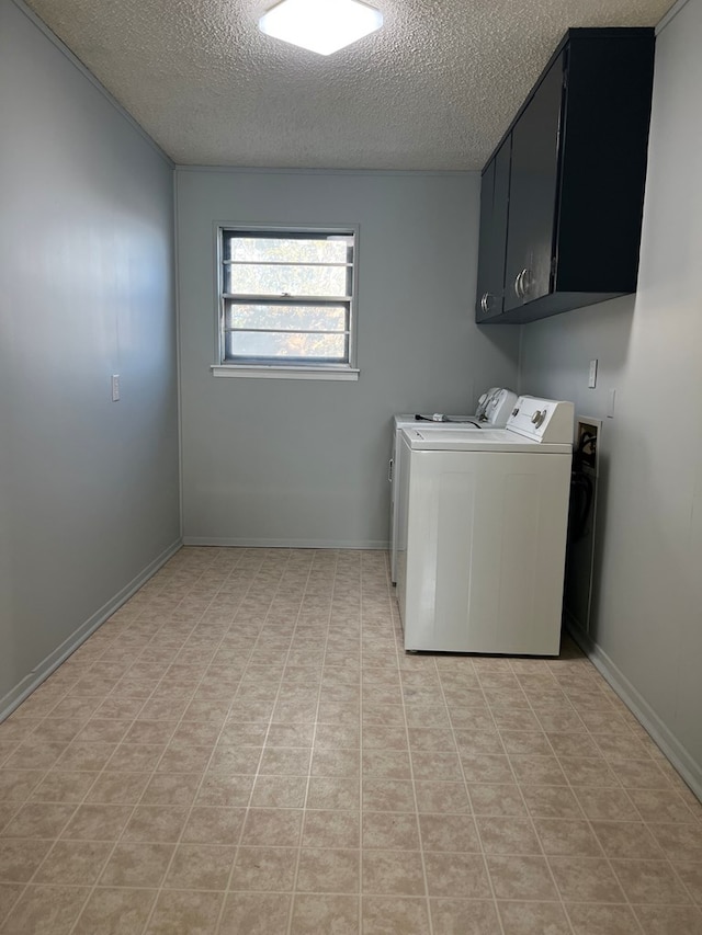 washroom featuring cabinets, a textured ceiling, and washer and clothes dryer