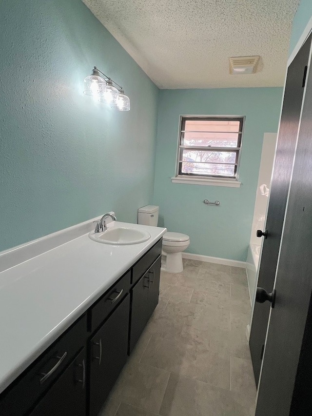 bathroom with vanity, a bath, a textured ceiling, and toilet