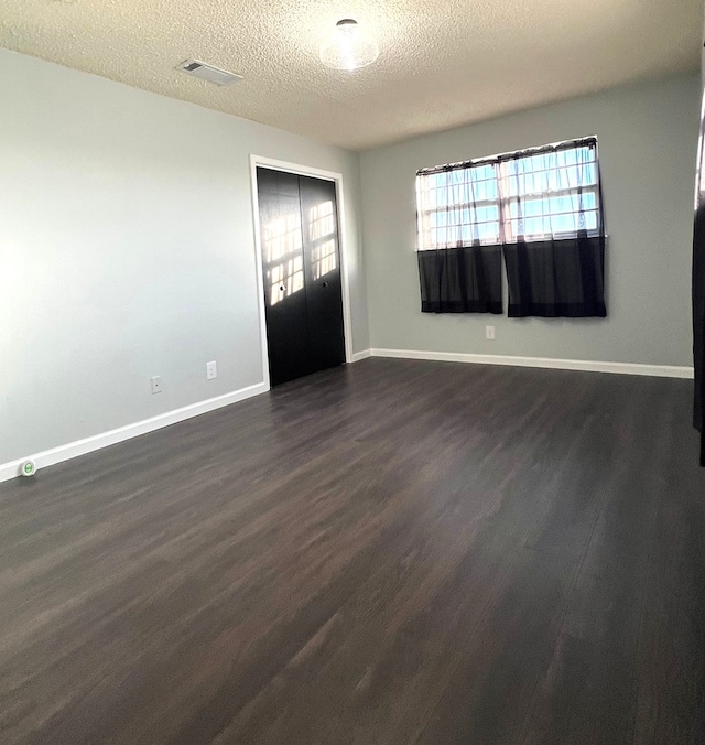 spare room featuring dark hardwood / wood-style floors and a textured ceiling